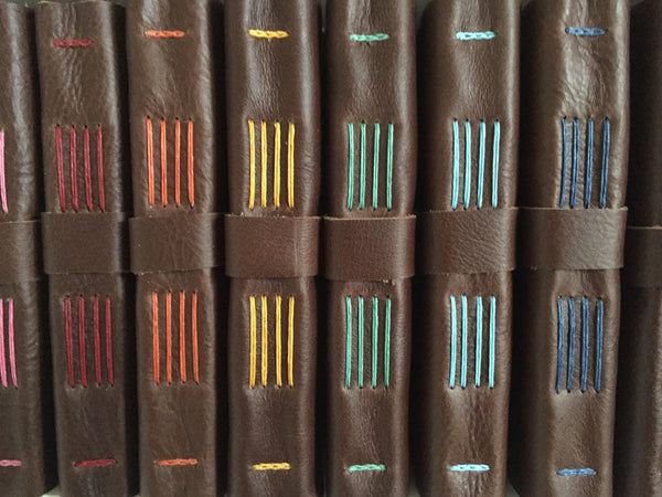 Spines of Chocolate Brown Leather Journals Sewn with different thread colors